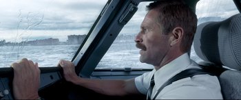 Movie still from “Sully” (2016), directed by Clint Eastwood – A man driving a car on a road; Close Up shot, Over the shoulder angle