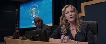 Movie still from “Sully” (2016), directed by Clint Eastwood – A woman sitting in front of a microphone in front of a man; Close Up shot, Over the shoulder angle