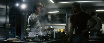 Movie still from “Sunshine” (2007), directed by Danny Boyle – A man holding a banana in a kitchen while another man watches; Medium shot, Low angle
