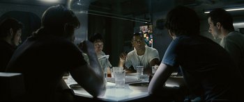 Movie still from “Sunshine” (2007), directed by Danny Boyle – A group of people sitting at a table with drinks; Medium shot, Over the shoulder angle