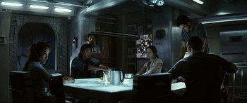 Movie still from “Sunshine” (2007), directed by Danny Boyle – A group of people sitting around a table; Medium shot, Over the shoulder angle