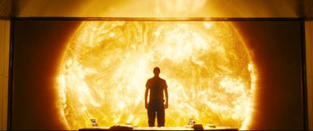 Movie still from “Sunshine” (2007), directed by Danny Boyle – A man standing in front of a large fire; Extreme Wide shot, Low angle
