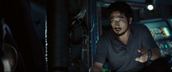 Movie still from “Sunshine” (2007), directed by Danny Boyle – A man standing in a dark room next to a bunch of wires; Close Up shot, Over the shoulder angle