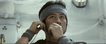 Movie still from “Sunshine” (2007), directed by Danny Boyle – A man wearing a head band while listening to music; Close Up shot, Low angle