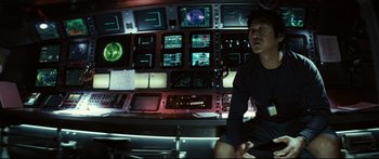 Movie still from “Sunshine” (2007), directed by Danny Boyle – A man sitting in front of a bunch of monitors; Medium shot, Over the shoulder angle