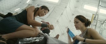 Movie still from “Sunshine” (2007), directed by Danny Boyle – A group of people sitting on the ground in a room; Medium shot, Over the shoulder angle