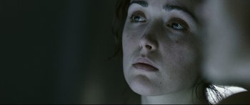 Movie still from “Sunshine” (2007), directed by Danny Boyle – A person's face in a dark room; Close Up shot, Over the shoulder angle