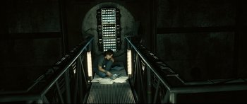 Movie still from “Sunshine” (2007), directed by Danny Boyle – A man sitting on the stairs of an underground tunnel; Wide shot, High angle