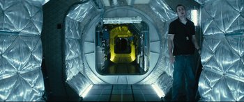 Movie still from “Sunshine” (2007), directed by Danny Boyle – A hallway in a building with a yellow light on the wall; Wide shot, Overhead angle