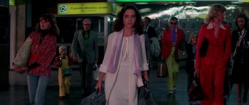 Movie still from “Suspiria” (1977), directed by Dario Argento – A woman in a white dress walking down a street; Medium shot, Low angle