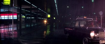 Movie still from “Suspiria” (1977), directed by Dario Argento – Cars driving down a wet street at night; Wide shot, Low angle