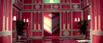 Movie still from “Suspiria” (1977), directed by Dario Argento – A red and white building with stairs going down it; Extreme Wide shot, High angle