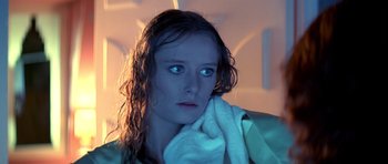 Movie still from “Suspiria” (1977), directed by Dario Argento – A woman with wet hair holding a white towel; Close Up shot, Low angle