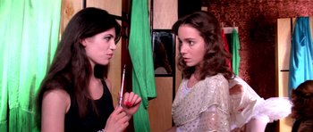 Movie still from “Suspiria” (1977), directed by Dario Argento – Two women one of whom is holding a brush and the other one is holding a green cloth; Close Up shot, Over the shoulder angle