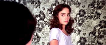 Movie still from “Suspiria” (1977), directed by Dario Argento – A young woman standing in front of a floral wall; Close Up shot, Over the shoulder angle