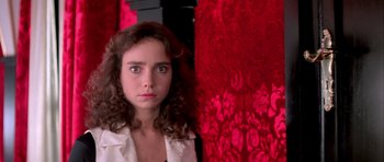 Movie still from “Suspiria” (1977), directed by Dario Argento – A young woman standing in front of a red curtain; Close Up shot, Low angle