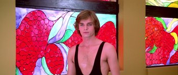 Movie still from “Suspiria” (1977), directed by Dario Argento – A man in a black tank top is in front of a painting; Close Up shot, Low angle