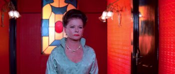 Movie still from “Suspiria” (1977), directed by Dario Argento – A woman in a blue dress standing next to a wall; Medium shot, Low angle