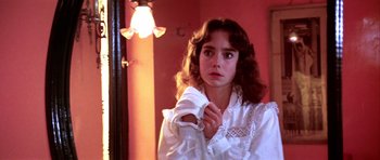 Movie still from “Suspiria” (1977), directed by Dario Argento – A young woman in a white shirt looking at a mirror; Close Up shot, Low angle