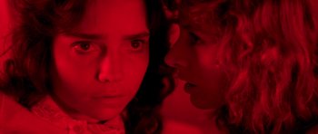 Movie still from “Suspiria” (1977), directed by Dario Argento – Two women in a red room looking at each other; Extreme Close Up shot, Low angle
