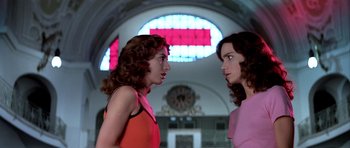 Movie still from “Suspiria” (1977), directed by Dario Argento – Two women are facing each other in front of a stained glass window; Medium shot, Low angle