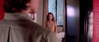 Movie still from “Suspiria” (1977), directed by Dario Argento – A woman standing in front of a mirror in a room; Medium shot, Over the shoulder angle