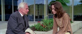 Movie still from “Suspiria” (1977), directed by Dario Argento – A man and a woman sitting next to each other on a bench; Medium shot, Over the shoulder angle