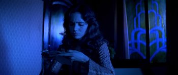 Movie still from “Suspiria” (1977), directed by Dario Argento – A woman is looking at her cell phone in the dark; Medium shot, Over the shoulder angle