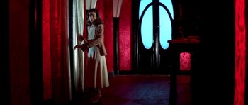Movie still from “Suspiria” (1977), directed by Dario Argento – A woman standing in front of a window in a room; Wide shot, Low angle