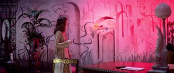 Movie still from “Suspiria” (1977), directed by Dario Argento – A woman standing in front of a wall with a painting on it; Wide shot, Over the shoulder angle