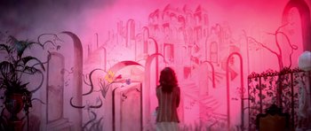 Movie still from “Suspiria” (1977), directed by Dario Argento – A woman standing in front of a wall with a painting on it; Wide shot, High angle