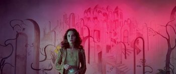 Movie still from “Suspiria” (1977), directed by Dario Argento – A woman standing in front of a wall with a painting on it; Medium shot, High angle
