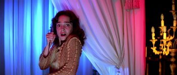 Movie still from “Suspiria” (1977), directed by Dario Argento – A young woman holding a cell phone up to her face; Medium shot, Low angle
