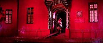 Movie still from “Suspiria” (1977), directed by Dario Argento – A woman in a white dress standing at the bottom of a staircase; Wide shot, Low angle
