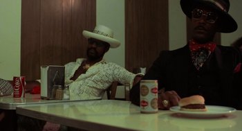 Movie still from “Taxi Driver” (1976), directed by Martin Scorsese – Two men sitting at a table with a can of soda; Medium shot, Low angle
