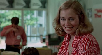 Movie still from “Taxi Driver” (1976), directed by Martin Scorsese – A young woman smiles brightly as she sits in front of a window; Close Up shot, Over the shoulder angle