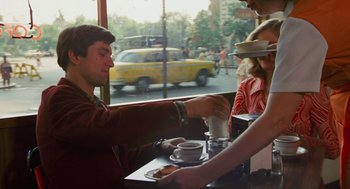Movie still from “Taxi Driver” (1976), directed by Martin Scorsese – A man sitting at a table in front of two women; Medium shot, Over the shoulder angle