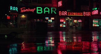 Movie still from “Taxi Driver” (1976), directed by Martin Scorsese – A neon sign that reads " terminal bar " on the side of the street; Extreme Wide shot, High angle