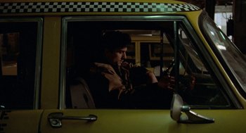 Movie still from “Taxi Driver” (1976), directed by Martin Scorsese – A man sitting in the driver's seat of a taxi cab; Medium shot, Low angle