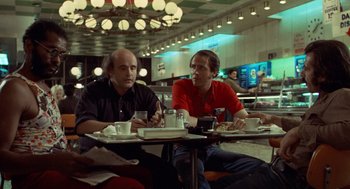 Movie still from “Taxi Driver” (1976), directed by Martin Scorsese – Two men sitting at a table with coffee and a newspaper; Medium shot, Over the shoulder angle