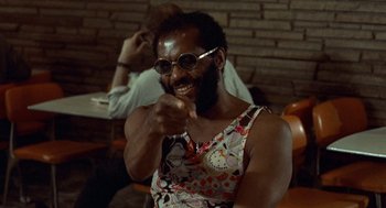 Movie still from “Taxi Driver” (1976), directed by Martin Scorsese – A man with a hello kitty tank top is pointing at the camera; Medium shot, Low angle