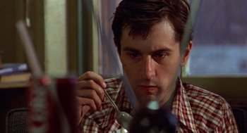 Movie still from “Taxi Driver” (1976), directed by Martin Scorsese – A person holding a spoon; Close Up shot, High angle