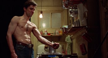 Movie still from “Taxi Driver” (1976), directed by Martin Scorsese – A shirtless man cooking in a kitchen with pots and pans on the stove; Medium shot, Low angle
