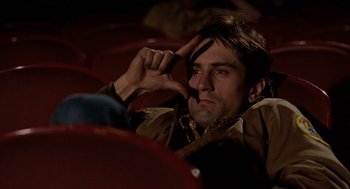 Movie still from “Taxi Driver” (1976), directed by Martin Scorsese – A man laying on the ground with his fingers in his ears; Close Up shot, Low angle