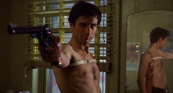 Movie still from “Taxi Driver” (1976), directed by Martin Scorsese – A shirtless man holding a gun in a room; Medium shot, Low angle