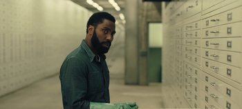 Movie still from “Tenet” (2020), directed by Christopher Nolan – A man with a beard wearing a green glove; Medium shot, Over the shoulder angle