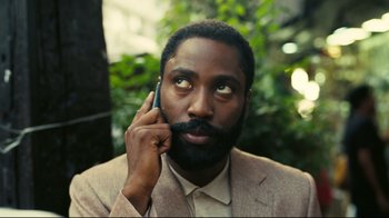 Movie still from “Tenet” (2020), directed by Christopher Nolan – A man with a beard is talking on a cell phone; Close Up shot, High angle