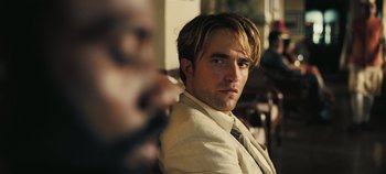 Movie still from “Tenet” (2020), directed by Christopher Nolan – A person wearing a suit and tie; Close Up shot, Over the shoulder angle