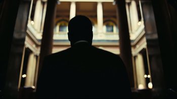 Movie still from “Tenet” (2020), directed by Christopher Nolan – A man standing in front of a large building; Medium shot, Low angle