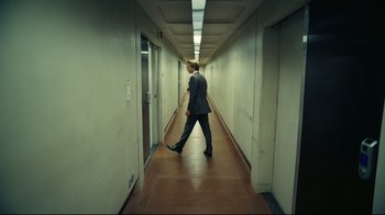 Movie still from “Tenet” (2020), directed by Christopher Nolan – A man in a suit walking down a long hallway; Wide shot, High angle